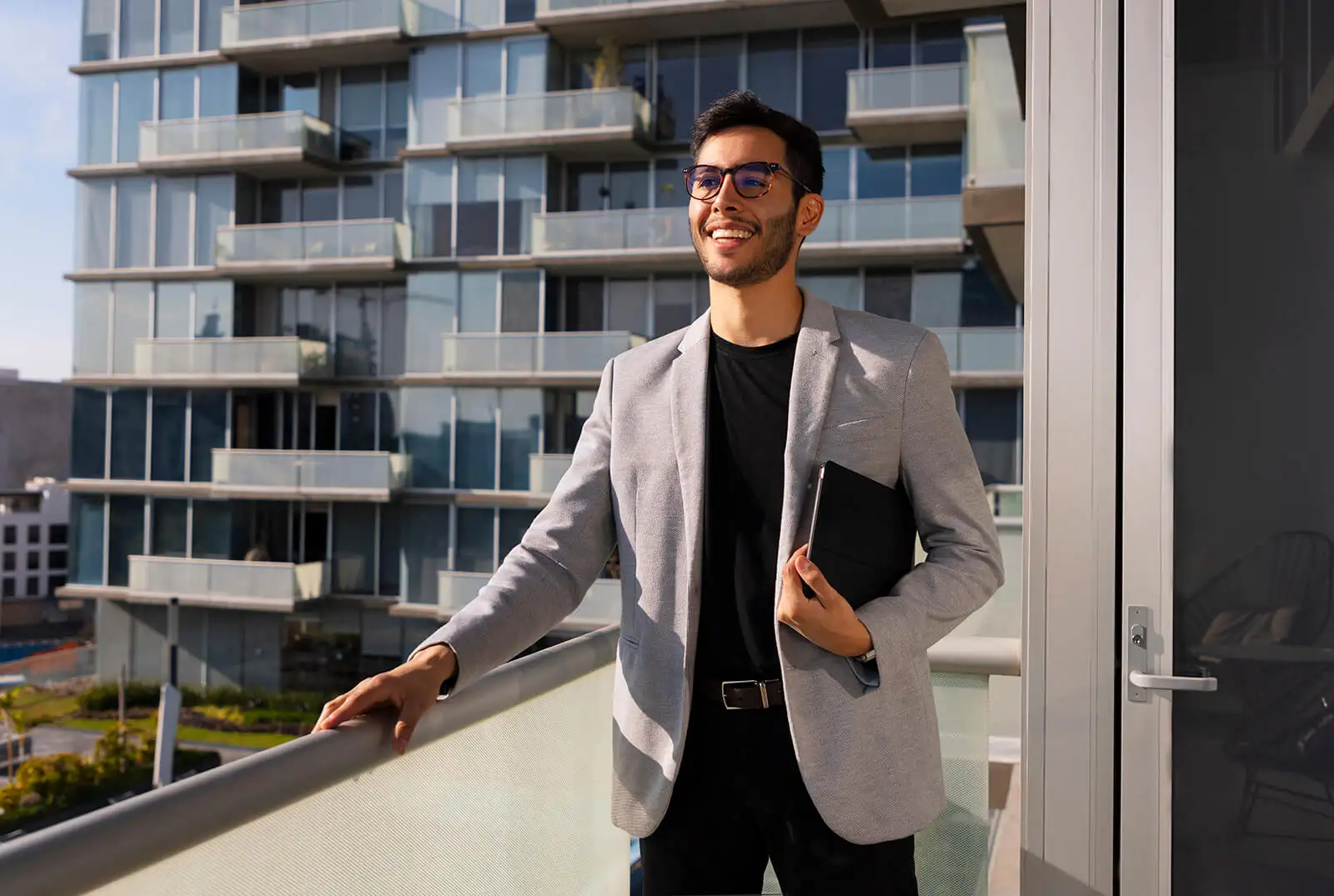 Young professional looking very pleased on a balcony with a view.